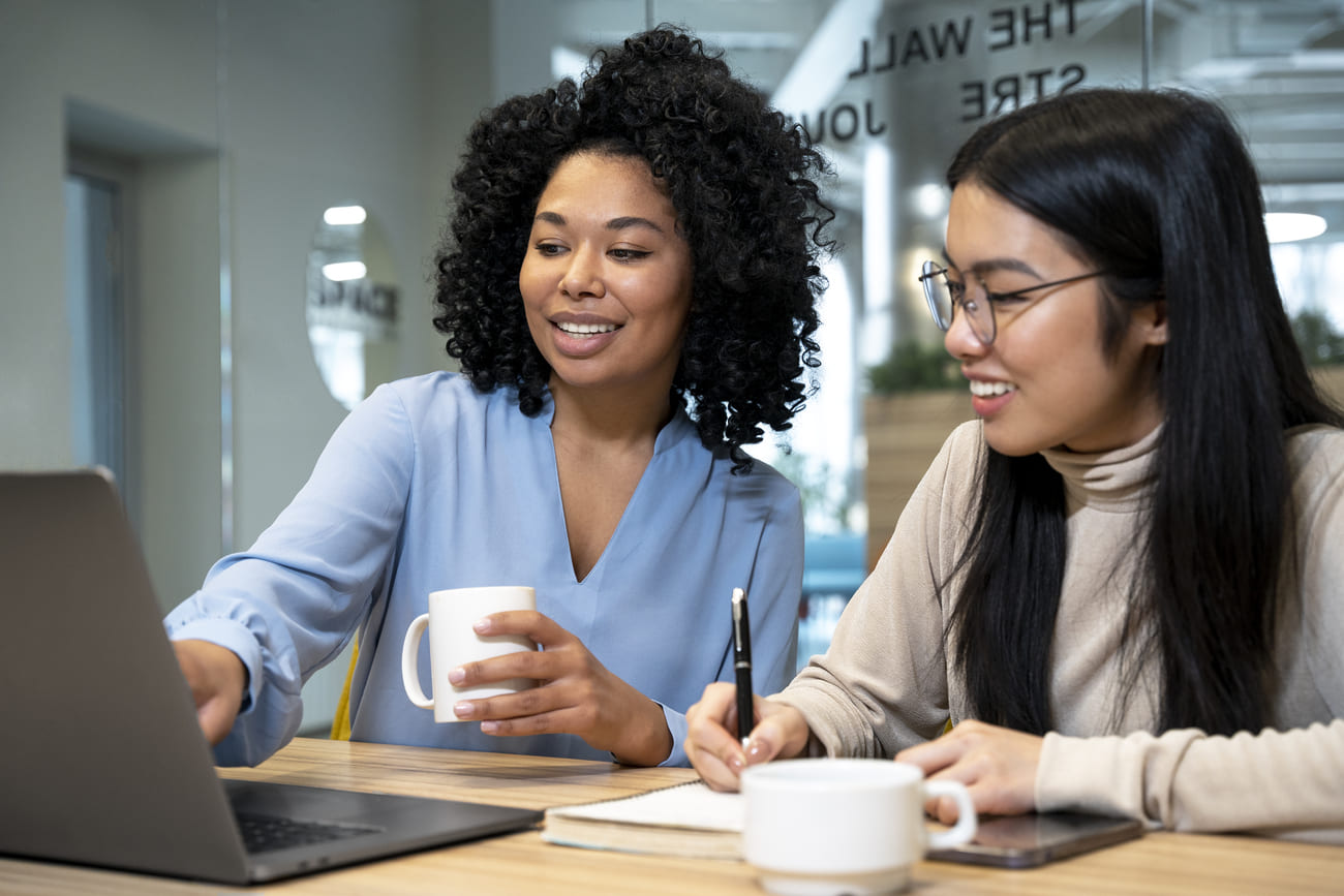 Colaboradora de empresa ensinando estagiária em programa de voluntariado corporativo