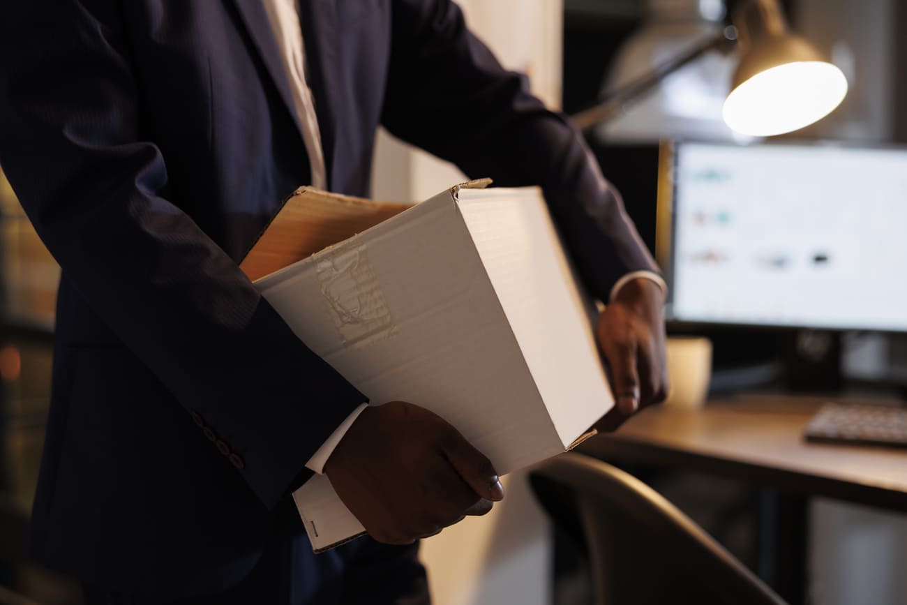 Executivo saindo com caixas na mão após sair da empresa, fenômeno conhecido como turnover